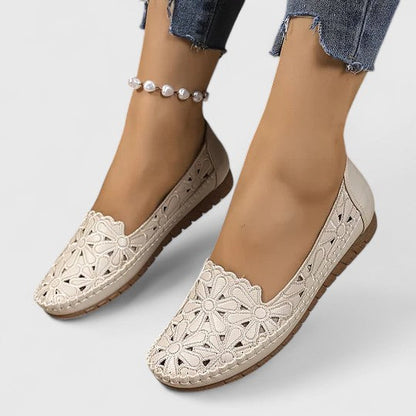 Beige - Women's slip-on loafers featuring a faux-leather upper with intricate floral cutouts and a flat, textured sole.