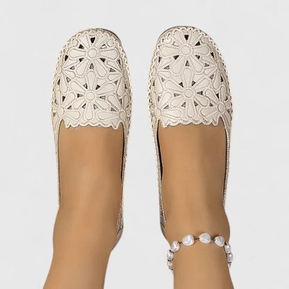 White - Women's slip-on loafers featuring a faux-leather upper with intricate floral cutouts and a flat, textured sole.