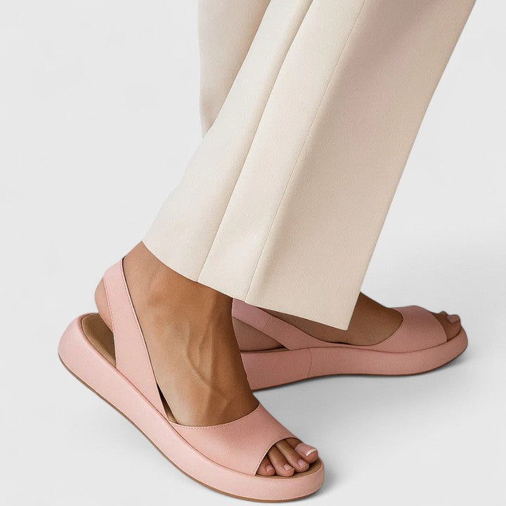 Faux-leather platform sandals featuring a wide front strap, open toe, and a continuous slingback strap on a thick cushioned sole.