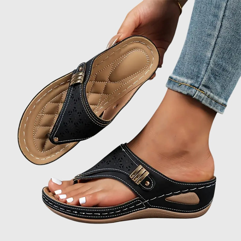 Black - Faux-leather wedge sandals featuring a slip-on thong design, laser-cut upper detailing, decorative metallic buckle, and prominent contrast stitching along a thick shock-absorbing sole.