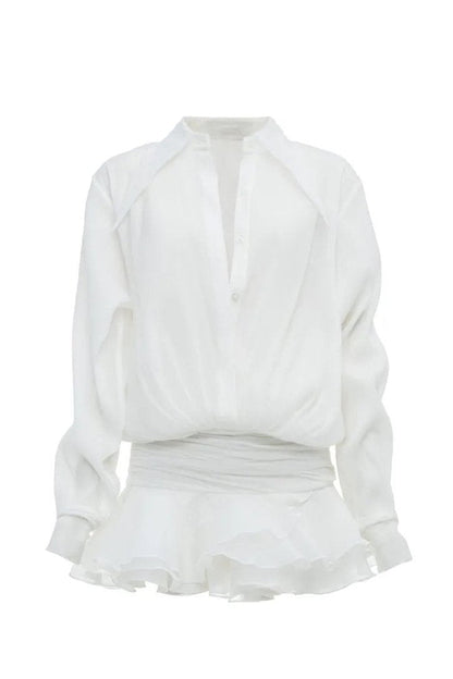 Front view of a woman wearing a sheer white mini shirt dress featuring a pointed collar, blouson top, wide ruched waist, and a short, tiered ruffled skirt.