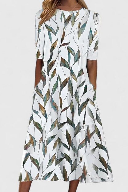 White 2 - A woman wearing a white midi-length A-line dress featuring a blue floral branch print, half sleeves, a boat neckline, and functional side pockets.
