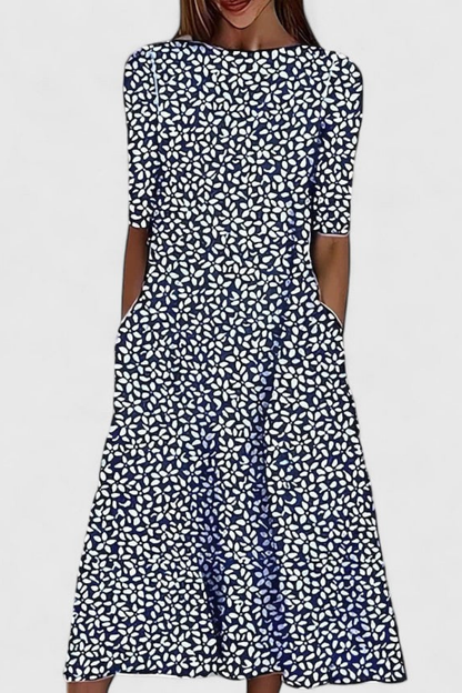 Dark Blue - A woman wearing a white midi-length A-line dress featuring a blue floral branch print, half sleeves, a boat neckline, and functional side pockets.