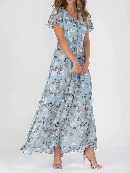 Light Blue - A woman wearing a peach-colored floral print chiffon maxi dress with flutter sleeves and a V-neck, showcasing a fluid, sweeping skirt.