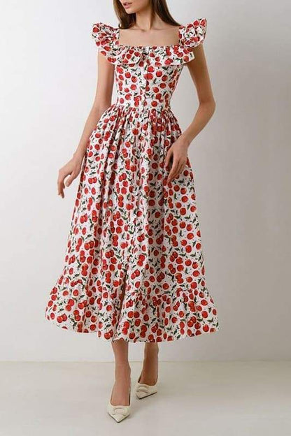 A woman wears a white fit-and-flare midi dress covered in a red cherry print, featuring a square neckline, ruffled cap sleeves, a fitted bodice, and a full skirt with a ruffled hem.