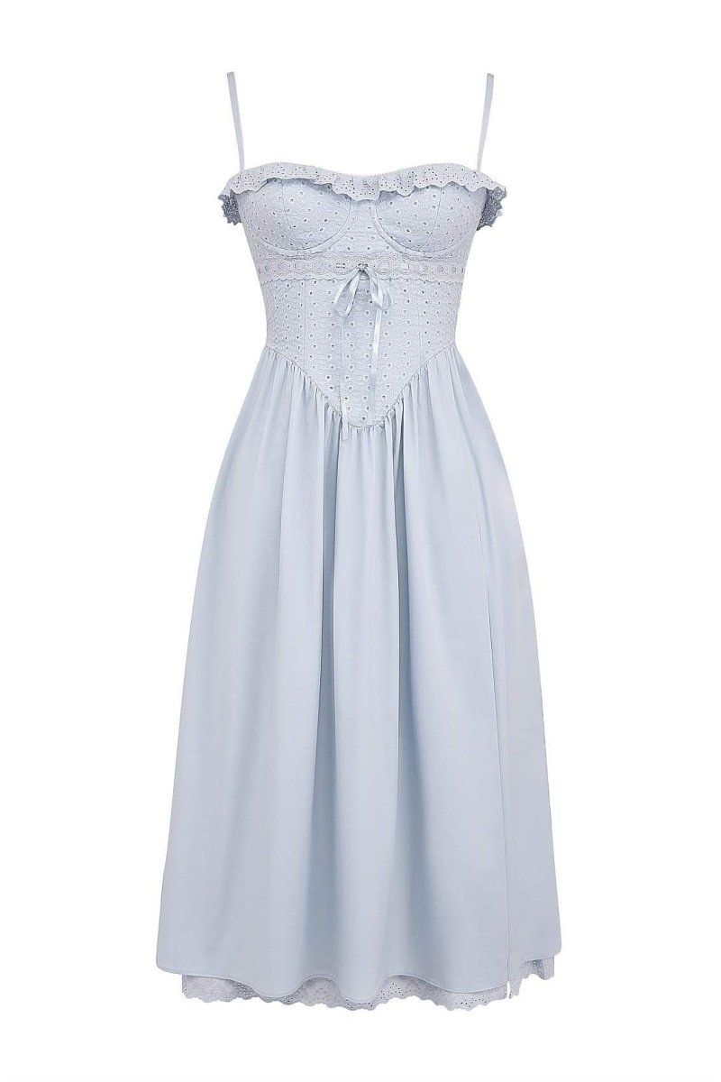 A woman models a light blue midi dress with spaghetti straps, a fitted broderie anglaise corset bodice, a flowing A-line skirt with a high side slit, and a matching broderie anglaise hem.