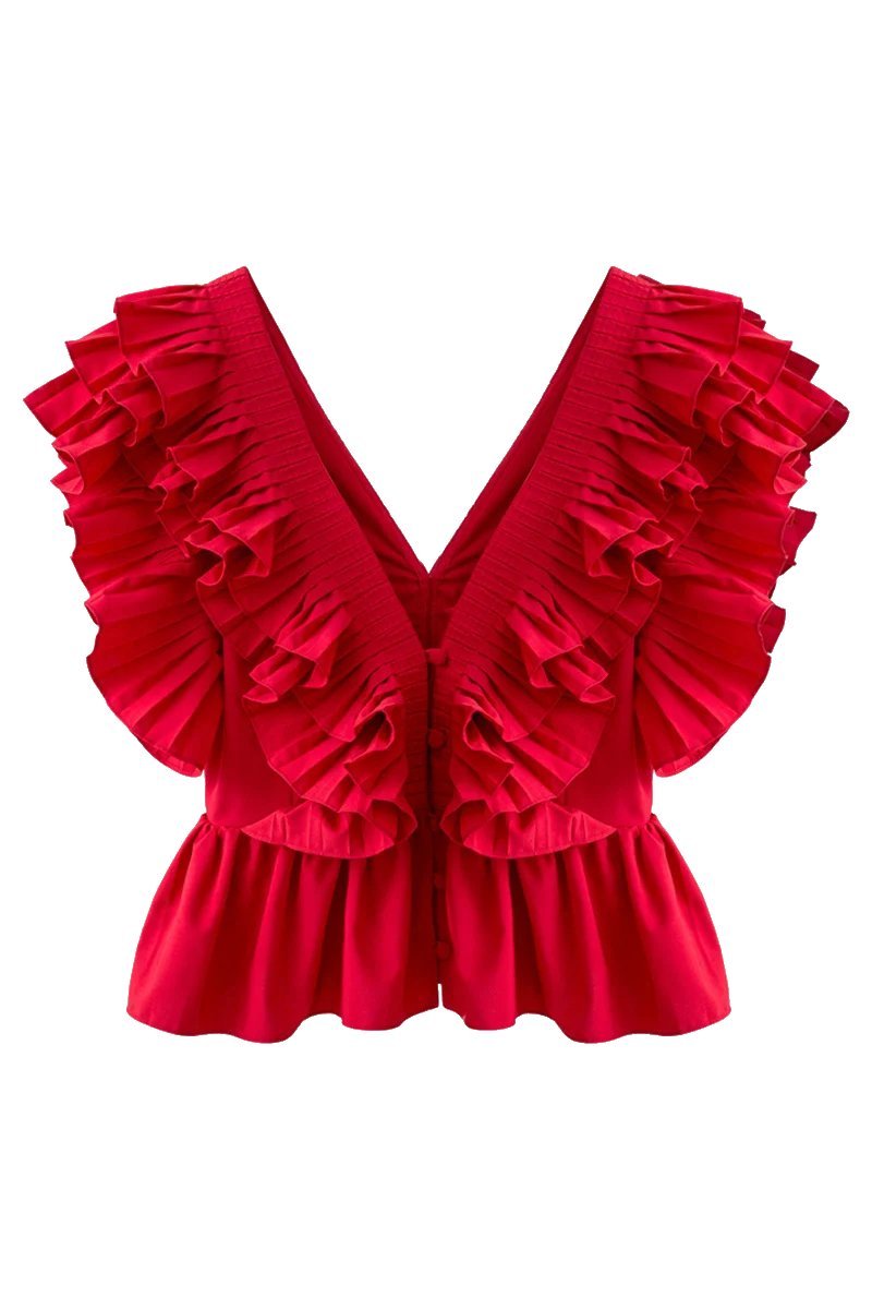 Red - A blonde woman modelling a bright red peplum blouse with dramatic, voluminous ruffles framing a V-neckline, paired with light wash jeans.