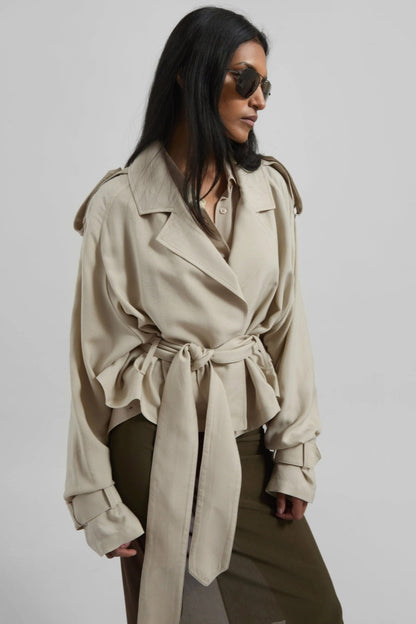 Women's cropped wrap trench jacket featuring a self-tie waist belt, wide lapels, shoulder epaulettes, and adjustable cuff straps in a fluid, relaxed fit.