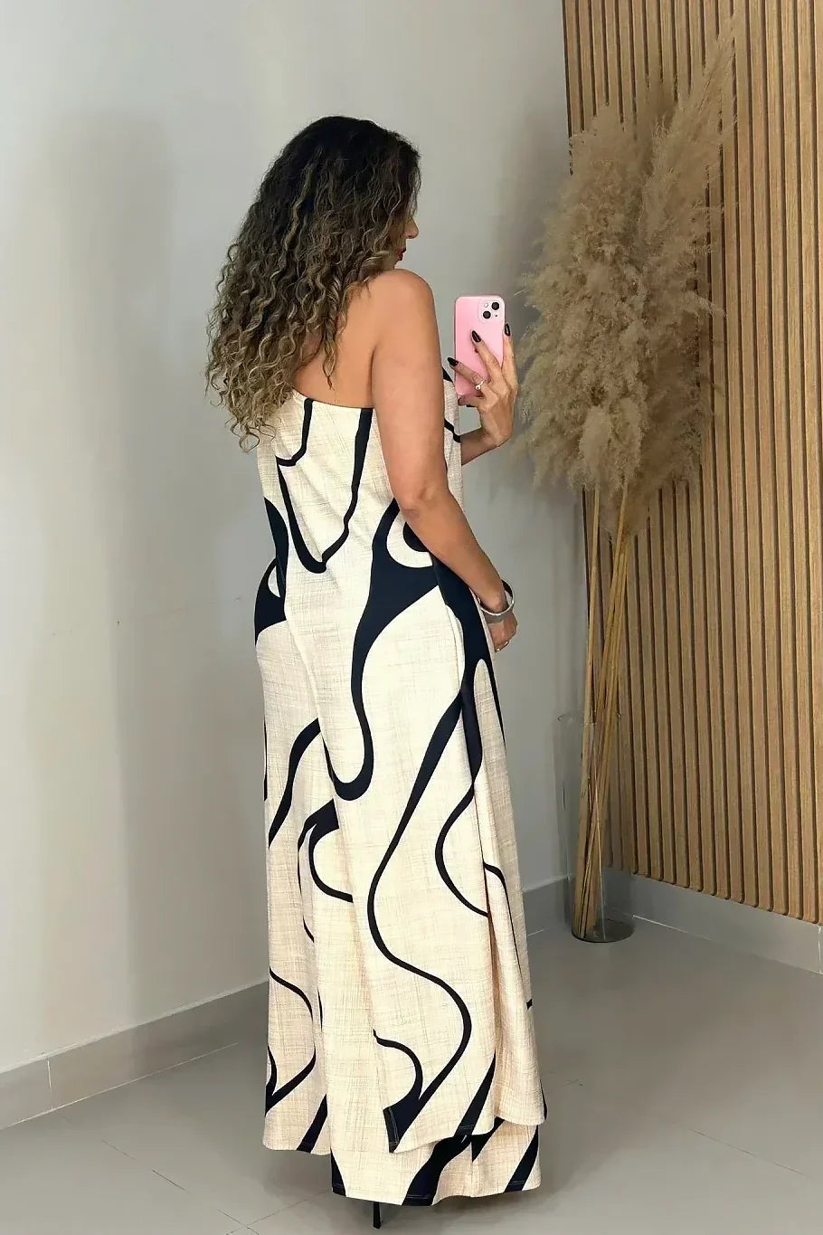 Woman in cream and black abstract print one-shoulder maxi dress