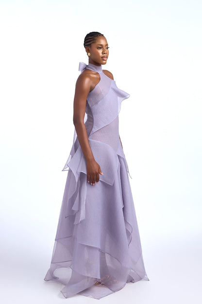 Purple - A woman wearing an elegant, floor-length gown featuring a high halter neckline, an asymmetrical layered bodice, and a voluminous tiered skirt made of sheer, crisp fabric.