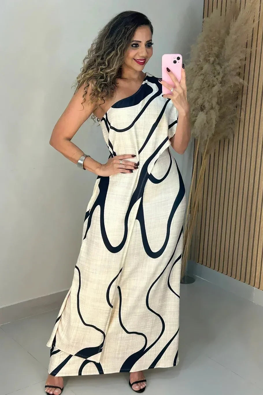 Woman in cream and black abstract print one-shoulder maxi dress