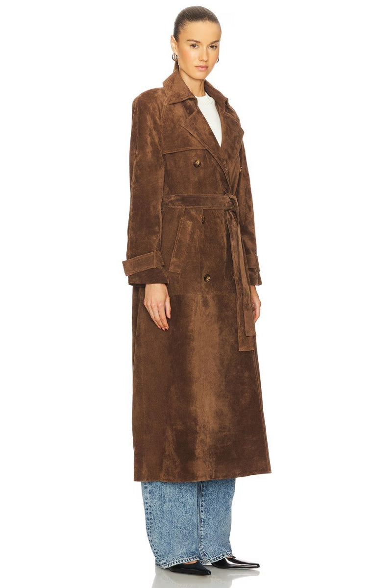 Brown - A woman wearing a long, brown suede-textured double-breasted trench coat with a self-tie belt, styled over jeans.