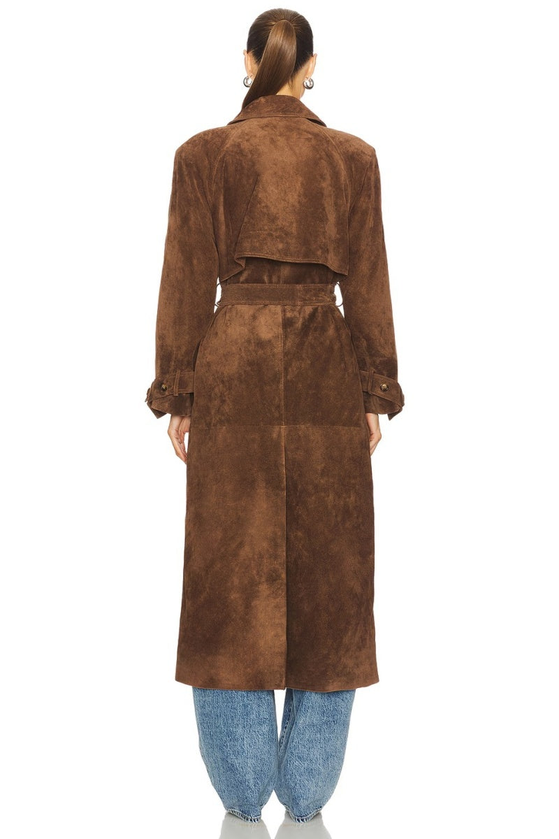 Brown - A woman wearing a long, brown suede-textured double-breasted trench coat with a self-tie belt, styled over jeans.