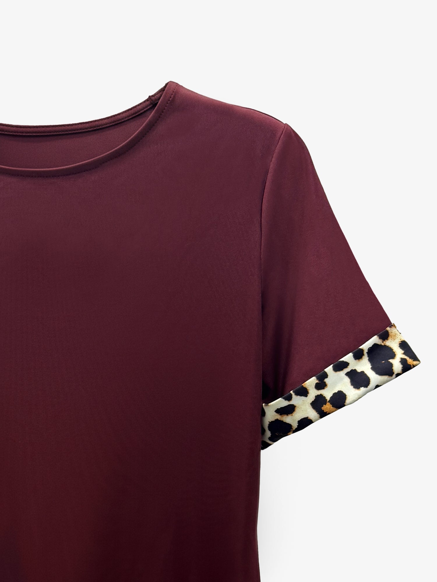 Burgundy - Woman wearing a short-sleeve shift mini dress with leopard print trim on the sleeves and hem, holding a small handbag