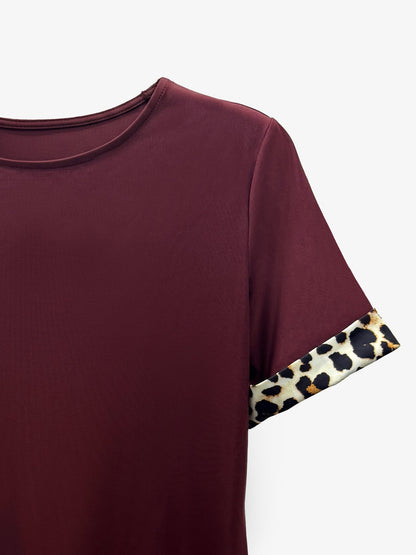 Burgundy - Woman wearing a short-sleeve shift mini dress with leopard print trim on the sleeves and hem, holding a small handbag