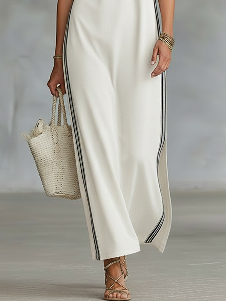White - Sleeveless collared maxi dress with a front half-button placket, contrast side stripes, and side hem slits, styled with a woven tote bag and strappy sandals.