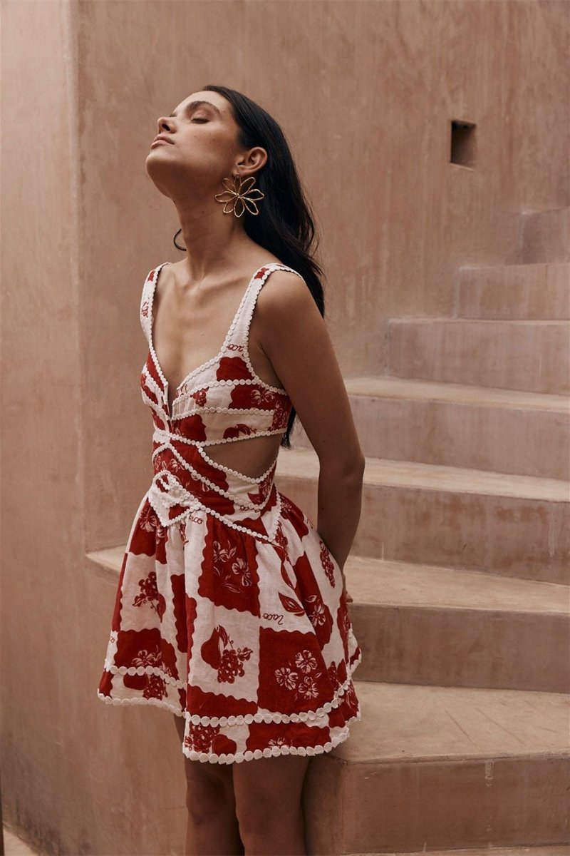Woman in red and white floral print mini dress posing on stairs