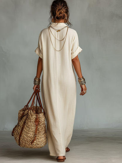 Beige - Woman wearing a relaxed-fit, floor-length linen maxi dress featuring a deep V-neckline, collar, short sleeves, front patch pocket, and intricate contrast embroidery around the neck.