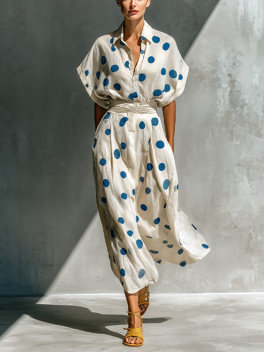 Off-White - Model walking in a flowing dotted midi dress featuring a collared V-neckline, short dolman sleeves, and a wide ruched waistband.
