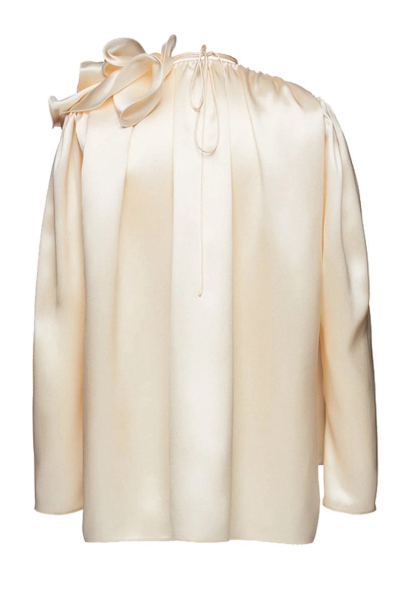 Woman in cream silk satin blouse with ruffle detail
