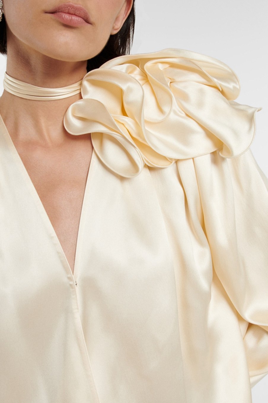 Woman in cream silk satin blouse with ruffle detail