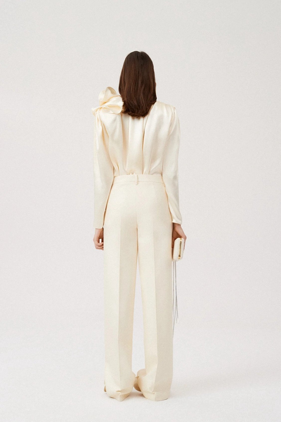 Woman in cream silk satin blouse with ruffle detail