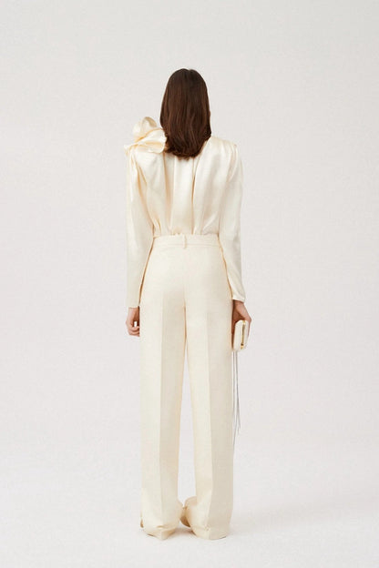 Woman in cream silk satin blouse with ruffle detail
