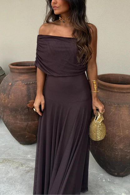 Brown - A woman wearing an elegant off-the-shoulder floor-length maxi dress featuring a ruched bodice and a sheer mesh overlay, styled with gold accessories.