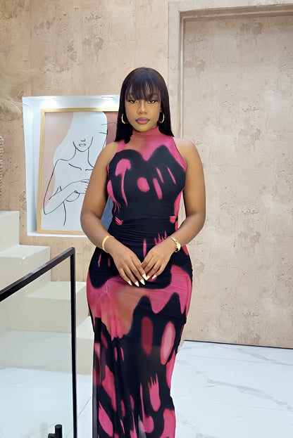 Black-pink - A woman wearing a sleeveless, mock-neck maxi dress featuring a bold abstract graphic print in a contemporary interior setting.