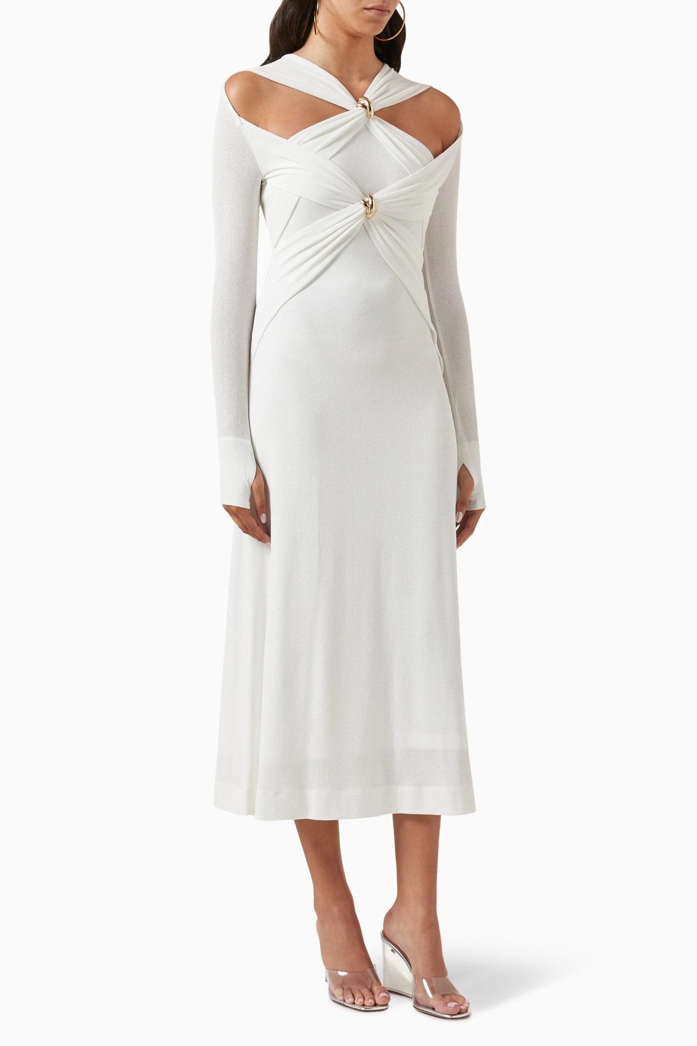Woman in black ribbed knit midi dress with cold shoulder and gold hardware detail.