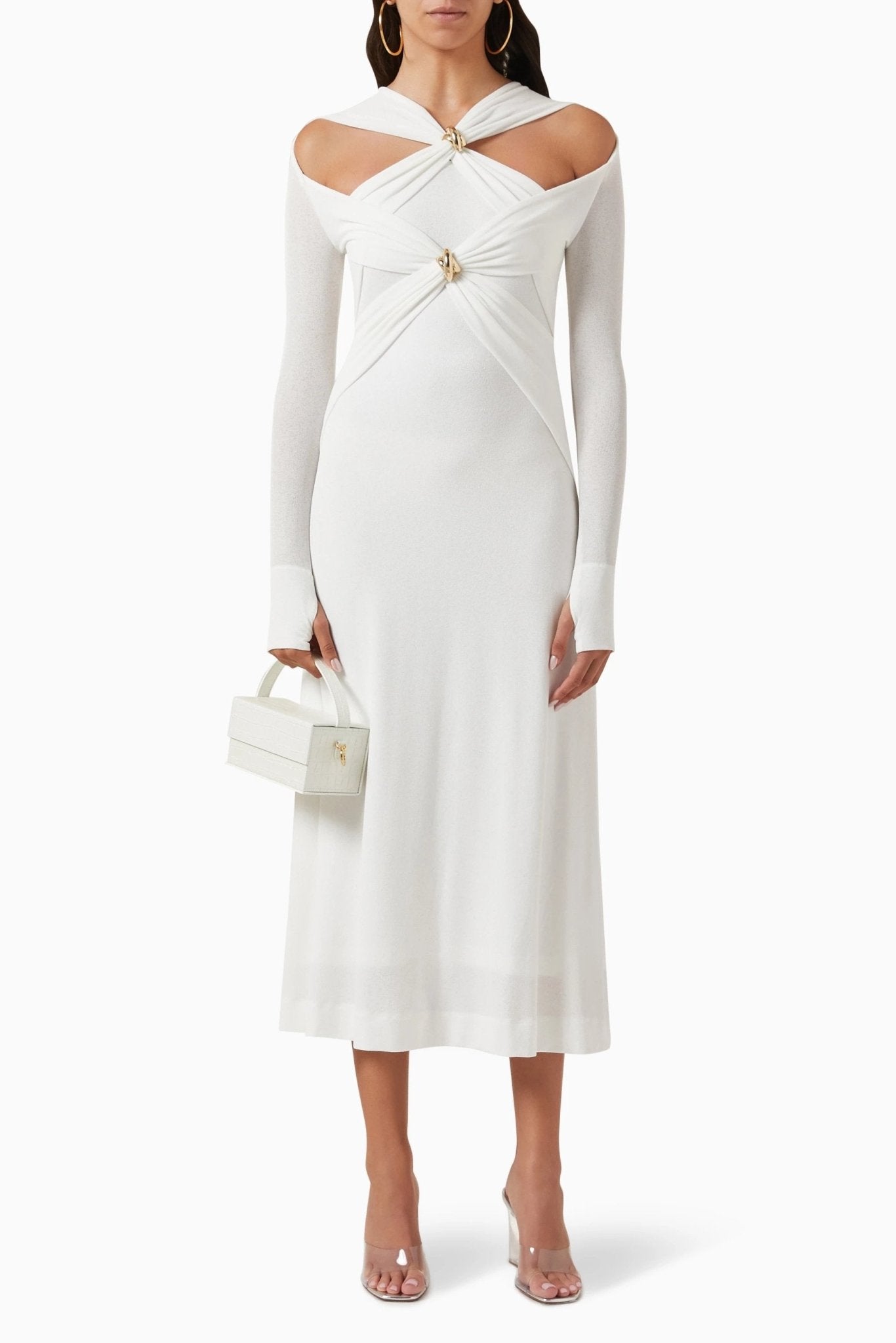 Woman in black ribbed knit midi dress with cold shoulder and gold hardware detail.