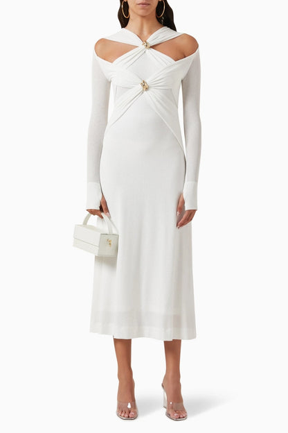 Woman in black ribbed knit midi dress with cold shoulder and gold hardware detail.