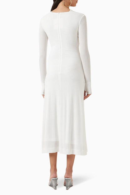 Woman in black ribbed knit midi dress with cold shoulder and gold hardware detail.