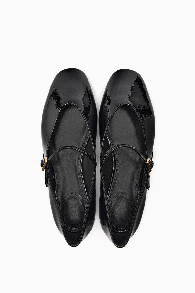 Top-down view of women's black glossy patent Mary Jane flats featuring a thin instep strap and small metallic buckle.