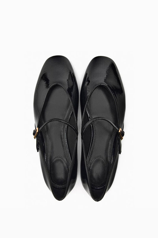 Top-down view of women's black glossy patent Mary Jane flats featuring a thin instep strap and small metallic buckle.