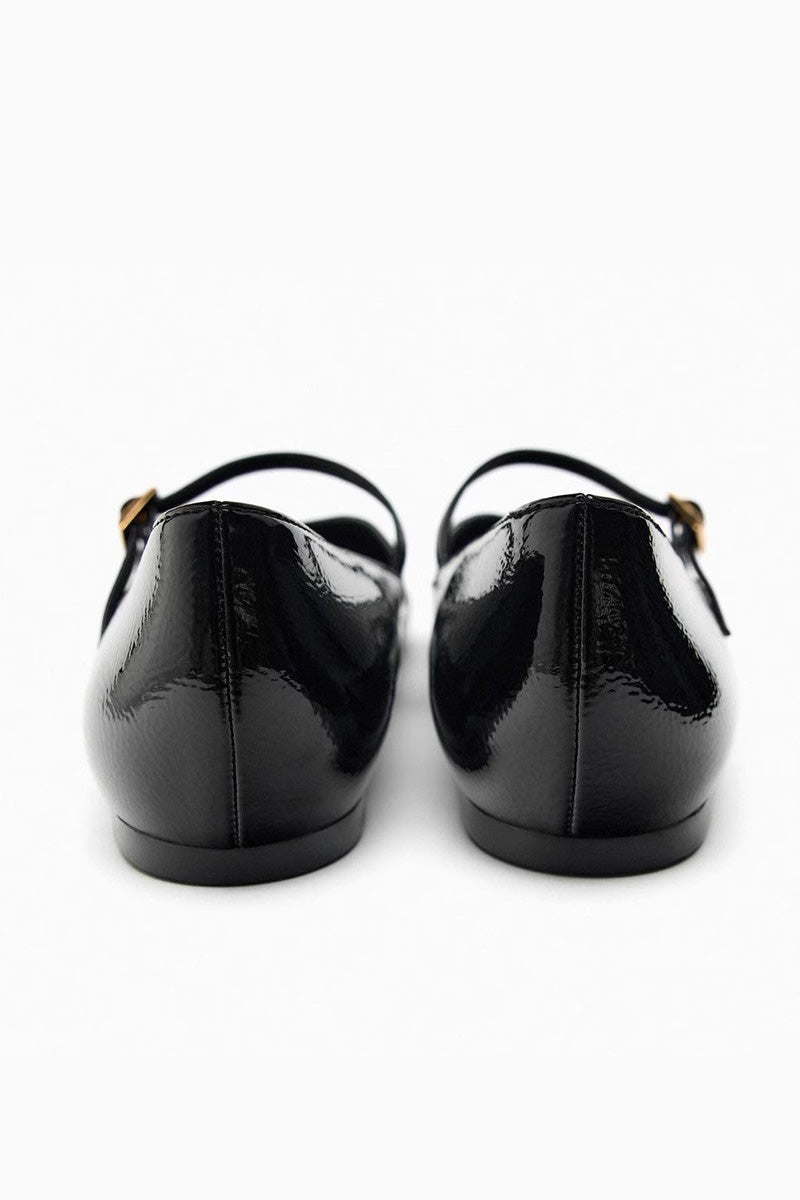 Black - Top-down view of women's black glossy patent Mary Jane flats featuring a thin instep strap and small metallic buckle.