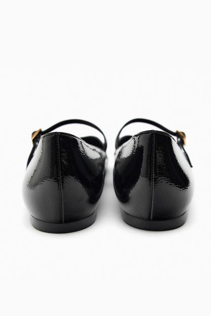 Black - Top-down view of women's black glossy patent Mary Jane flats featuring a thin instep strap and small metallic buckle.