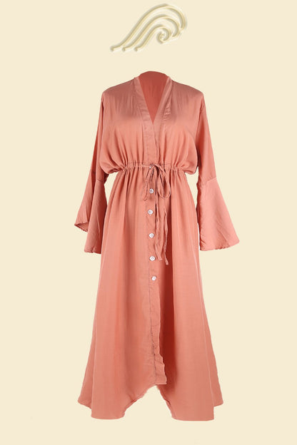 Full length shot of a woman in a terracotta lightweight polyester maxi cover-up with a deep V-neck, button-up front, drawstring waist, and bell sleeves.