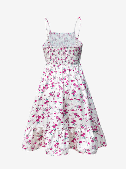 White - Woman wearing a floral print mini sundress with spaghetti straps, a smocked bodice, and a ruffle hem against a white textured wall