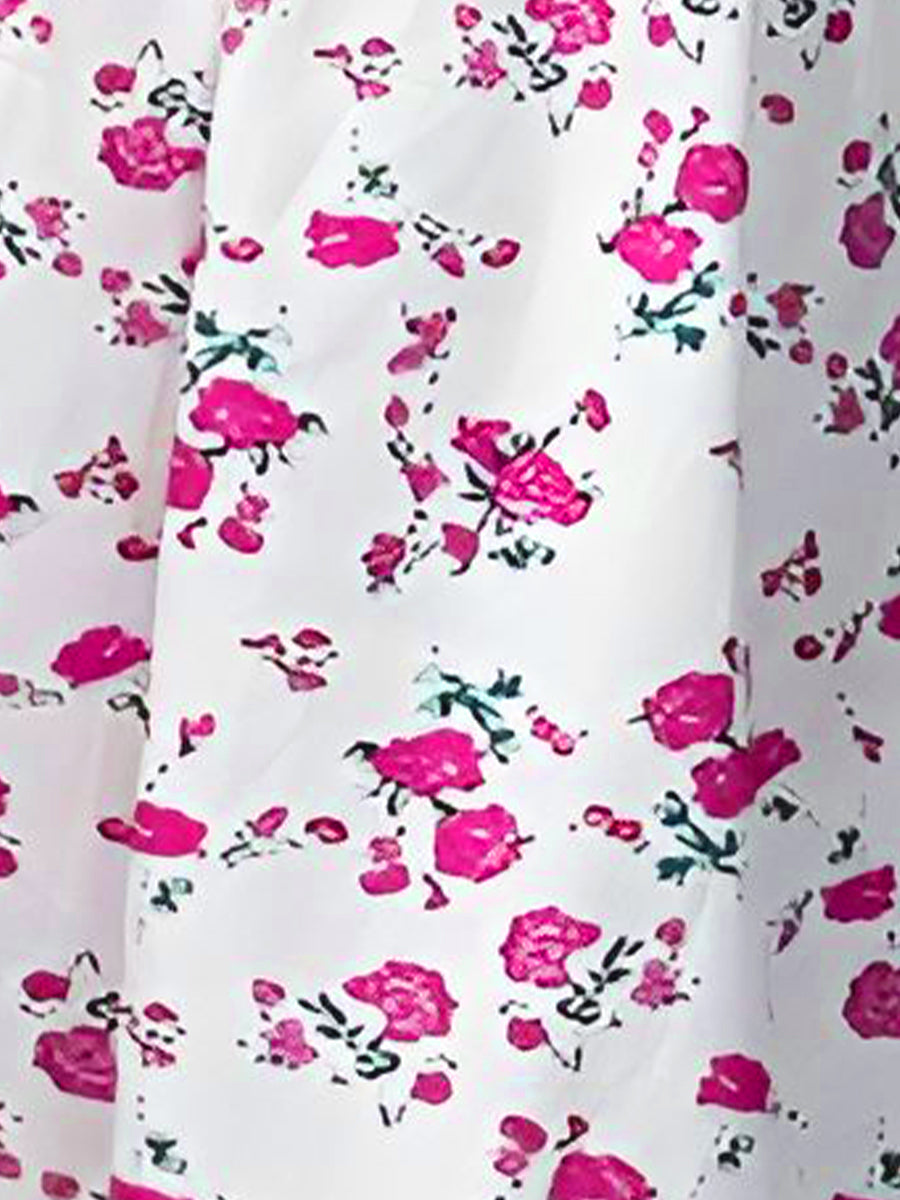 White - Woman wearing a floral print mini sundress with spaghetti straps, a smocked bodice, and a ruffle hem against a white textured wall
