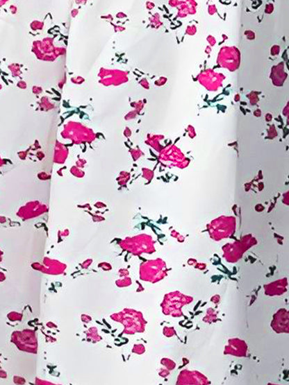 White - Woman wearing a floral print mini sundress with spaghetti straps, a smocked bodice, and a ruffle hem against a white textured wall