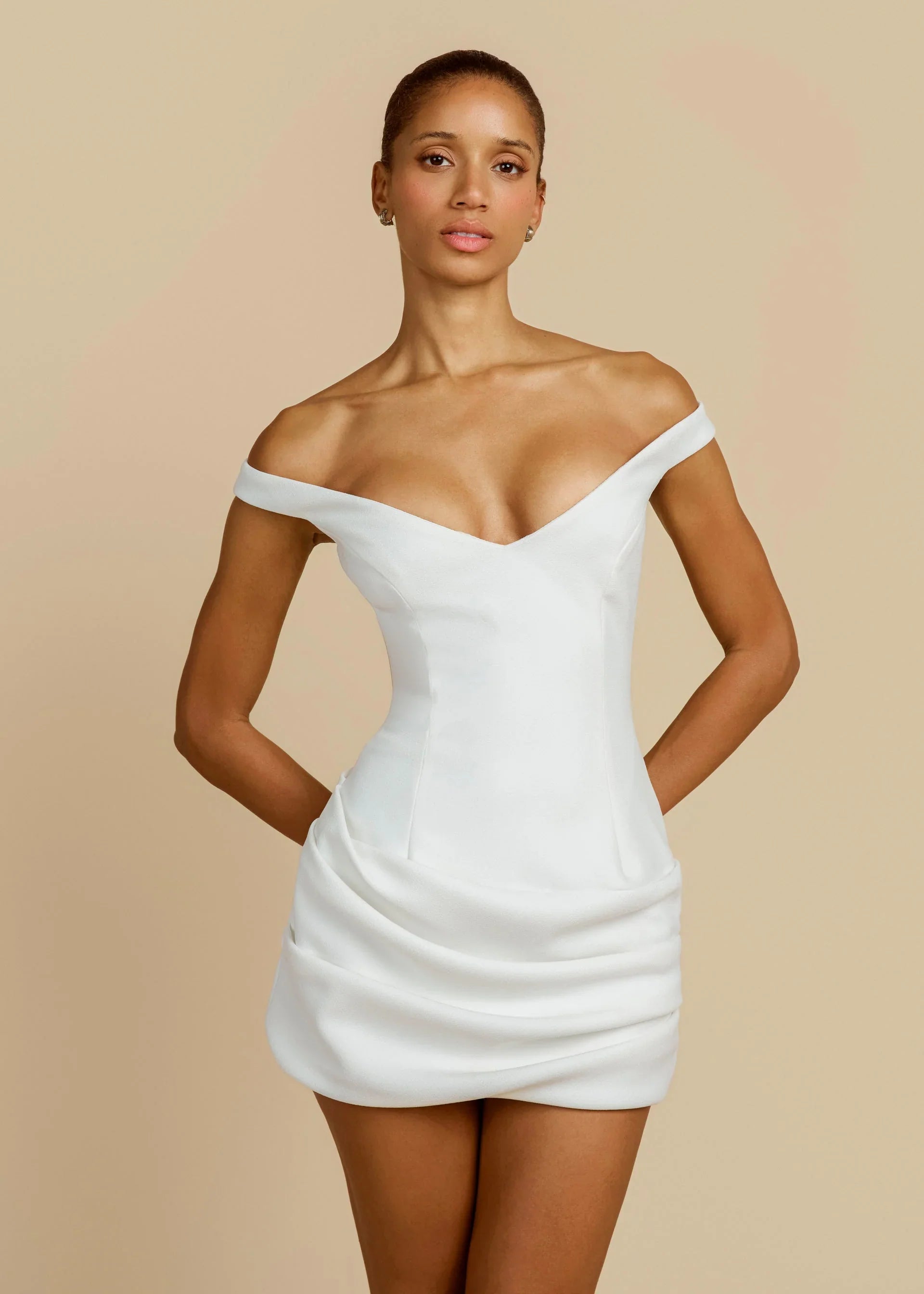 Women's white formal mini dress featuring an off-the-shoulder plunging neckline, structured bodice, and a heavily ruched draped skirt.