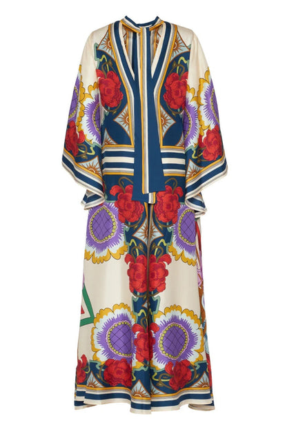 Multi - A model wears a floor-length satin maxi dress featuring a bold, colorful floral and geometric scarf print in cream, blue, red, and purple, designed with a deep V-neckline, long scarf collar, and wide flowing sleeves.