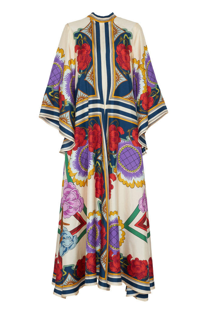 Multi - A model wears a floor-length satin maxi dress featuring a bold, colorful floral and geometric scarf print in cream, blue, red, and purple, designed with a deep V-neckline, long scarf collar, and wide flowing sleeves.