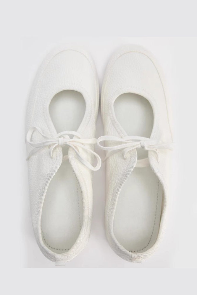 Women's white textured faux leather ballet flats with a delicate tie-front detail, viewed from above.