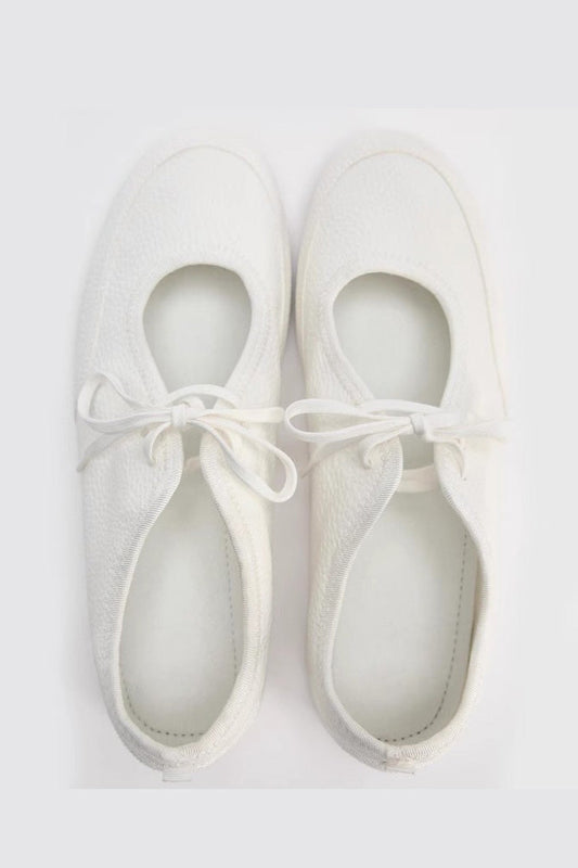 Women's white textured faux leather ballet flats with a delicate tie-front detail, viewed from above.