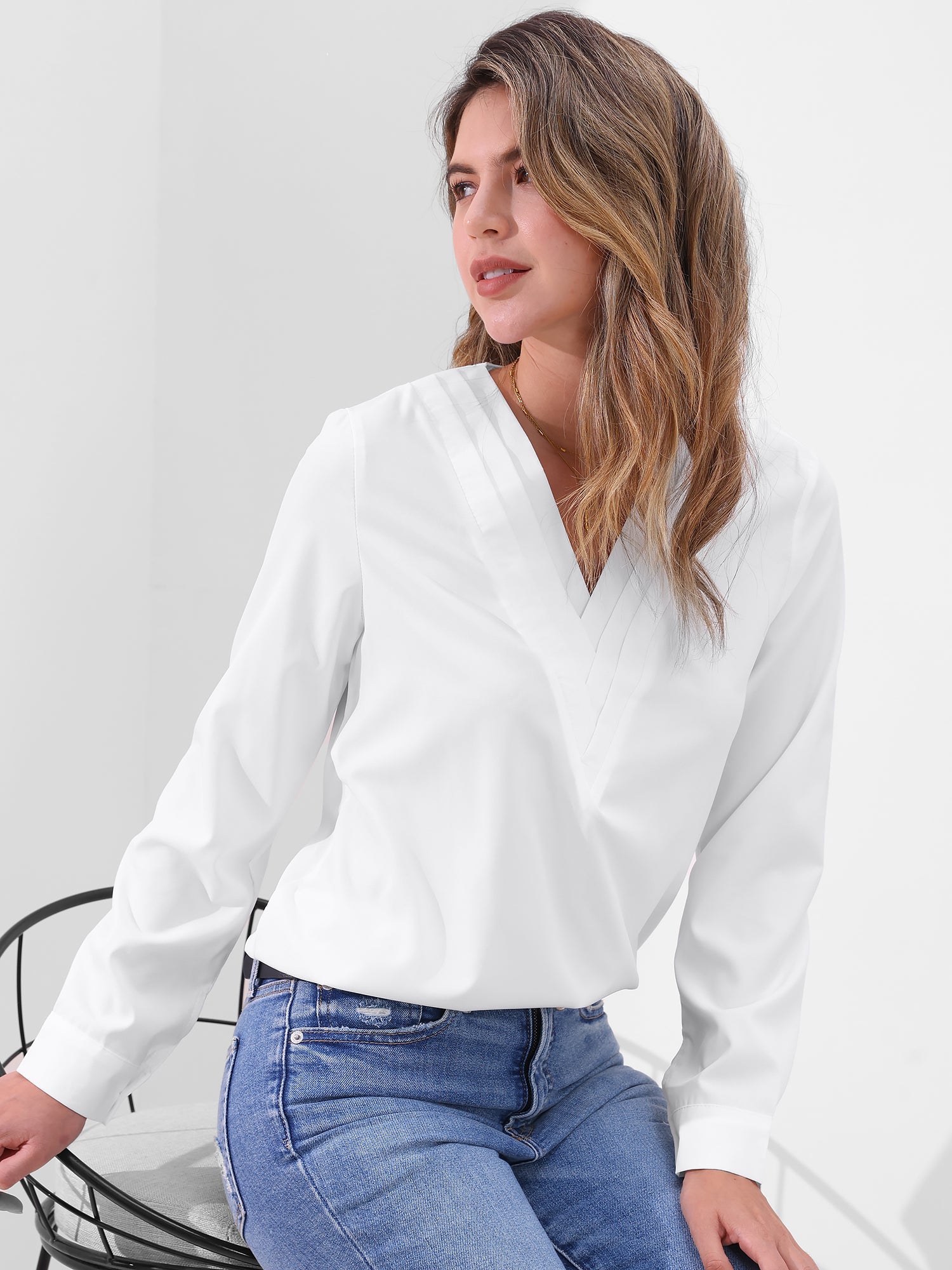 Pink - Women's long-sleeve blouse featuring a distinctive pleated V-neckline and buttoned cuffs, styled tucked into blue denim jeans.