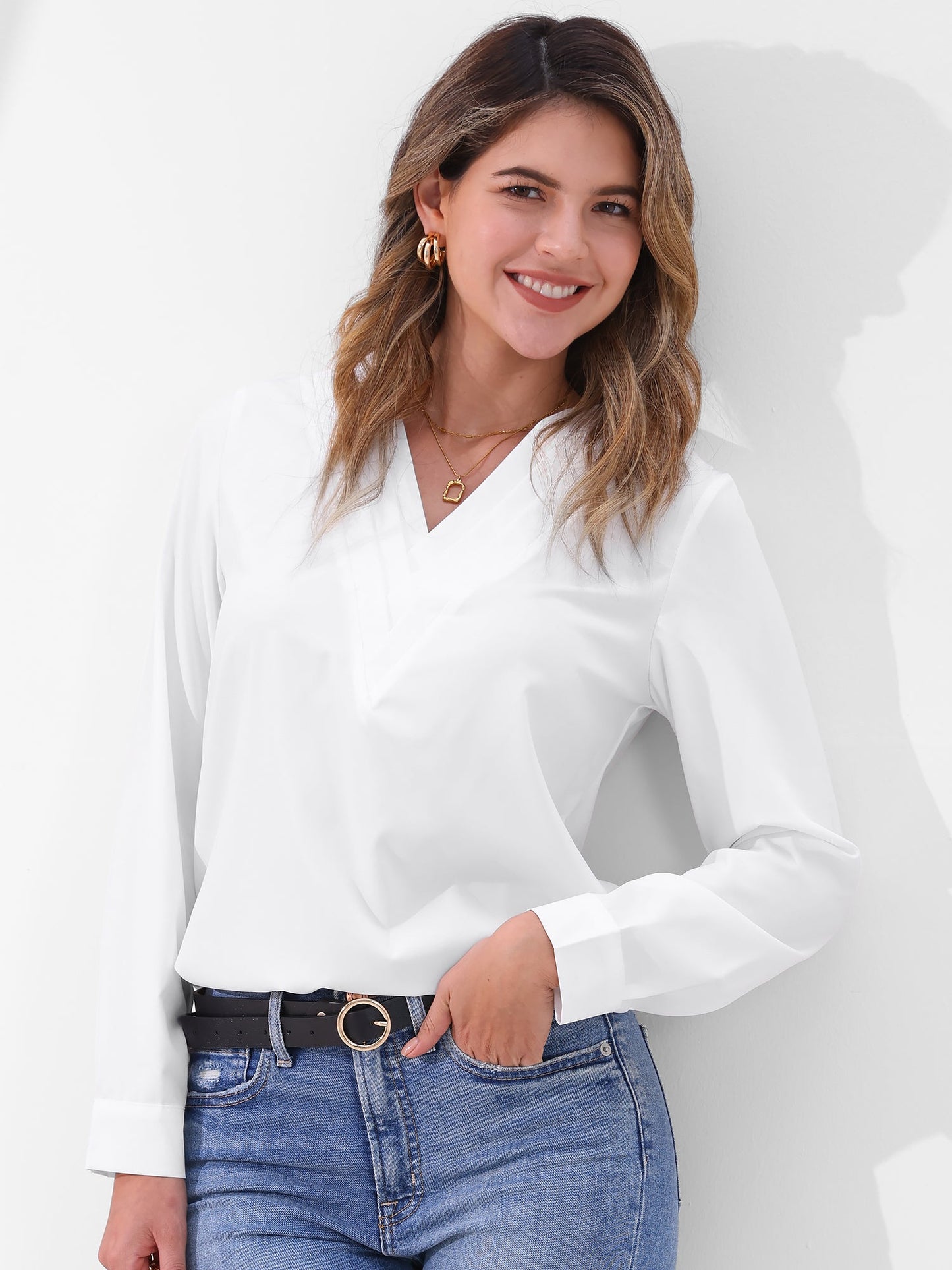 Pink - Women's long-sleeve blouse featuring a distinctive pleated V-neckline and buttoned cuffs, styled tucked into blue denim jeans.