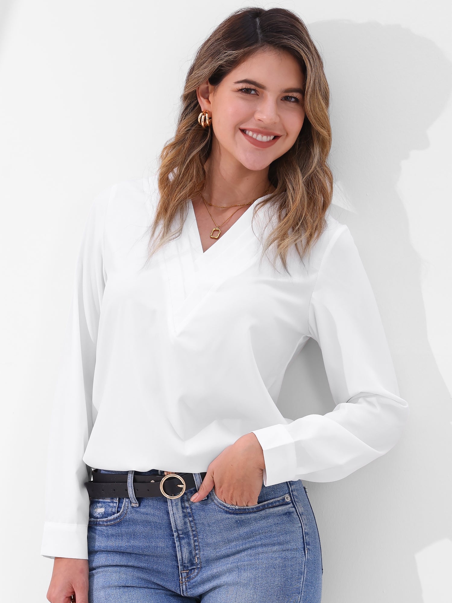 Pink - Women's long-sleeve blouse featuring a distinctive pleated V-neckline and buttoned cuffs, styled tucked into blue denim jeans.