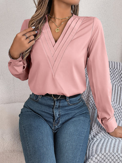 Pink - Women's long-sleeve blouse featuring a distinctive pleated V-neckline and buttoned cuffs, styled tucked into blue denim jeans.